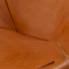Close-up of warm tan leather upholstery with visible stitching and a small metal rivet along a seam.
