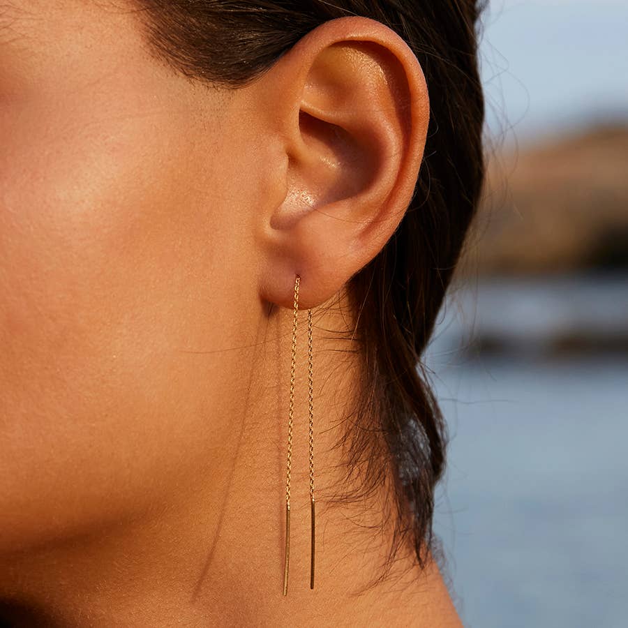 Close-up of an ear wearing a gold chain earring 