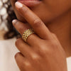 Close-up of a hand wearing a gold ring with a textured band.