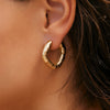 Gold hoop earring worn by a person with brown hair.