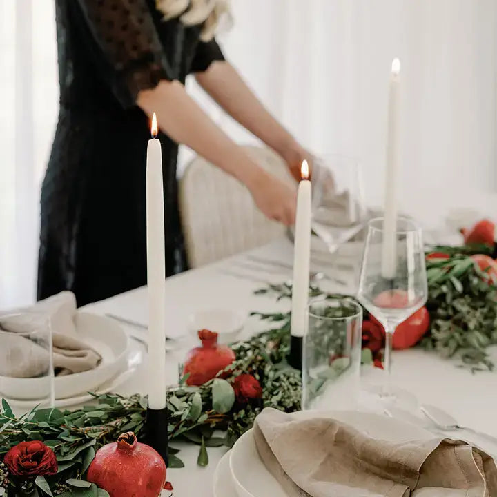 Woman setting a table with candles and pomegranates.