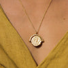 Gold pendant necklace on a yellow shirt.