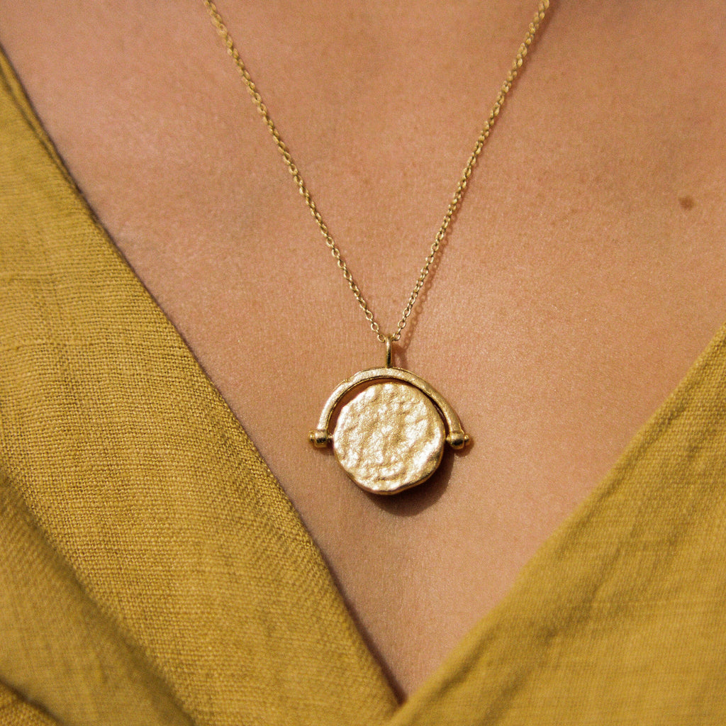 Gold pendant necklace on a yellow shirt.