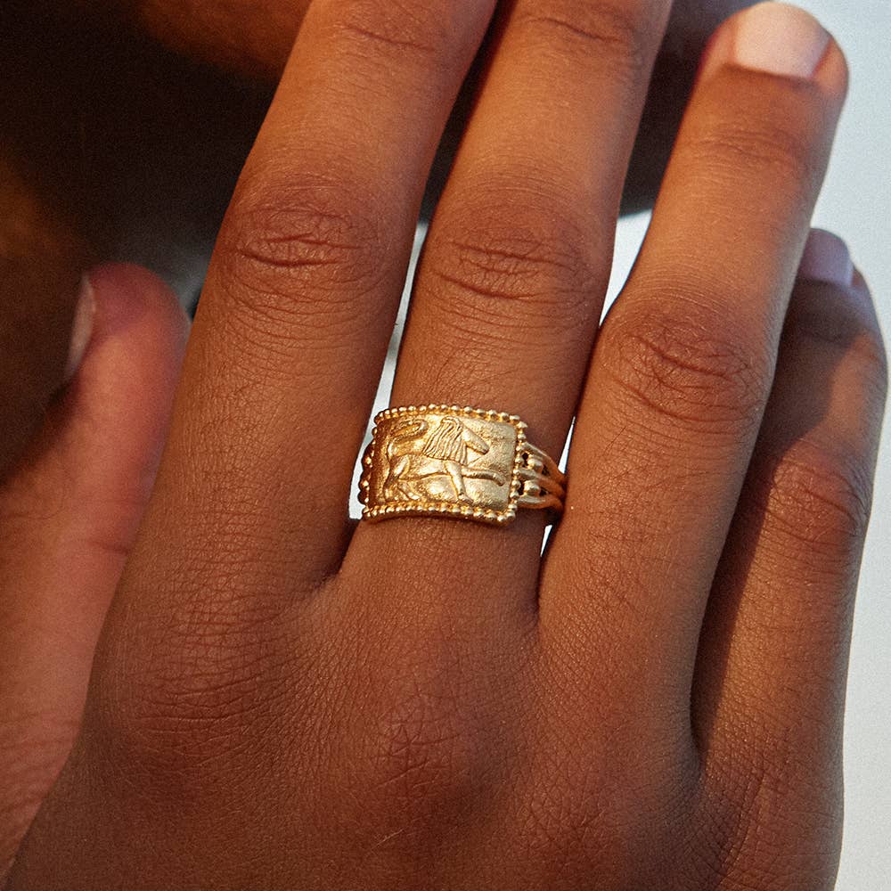 Gold ring with intricate lion design on a person's finger