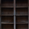 An empty rustic wooden bookcase with four shelves and weathered brown panels, shown from the front with the center door panel slightly open.