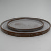 Two round ceramic plates with a rustic finish on a light gray background