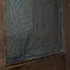 Close-up of a distressed, vintage-style metal door panel with a textured, embossed pattern of rivets on a weathered, dark gray surface, framed by a rustic brown wooden border.