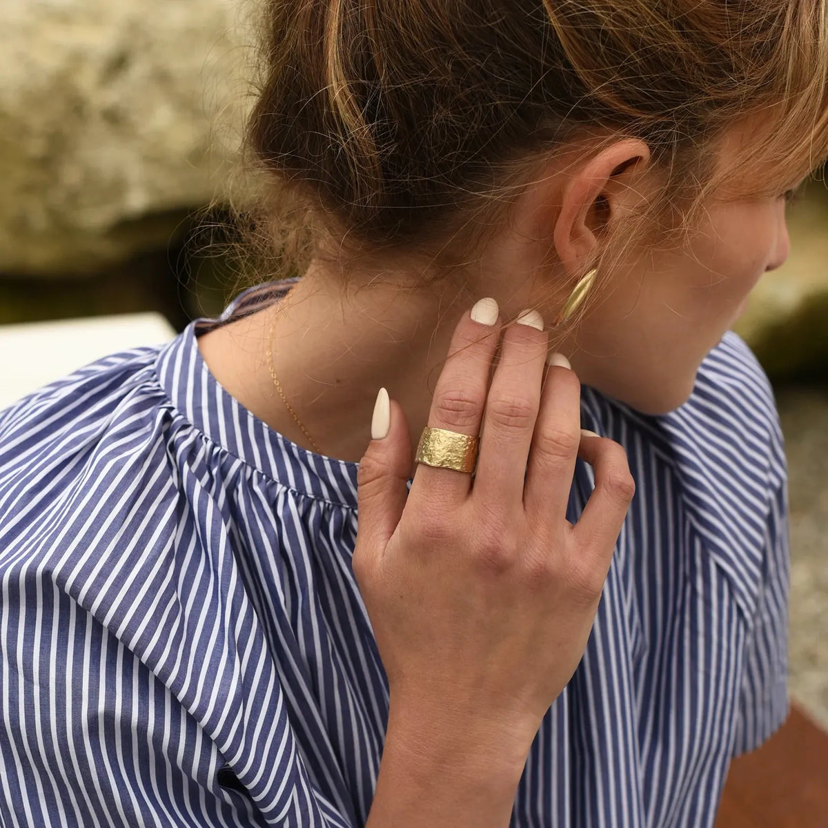 Woman wearing a gold ring, close-up of hand and neck.