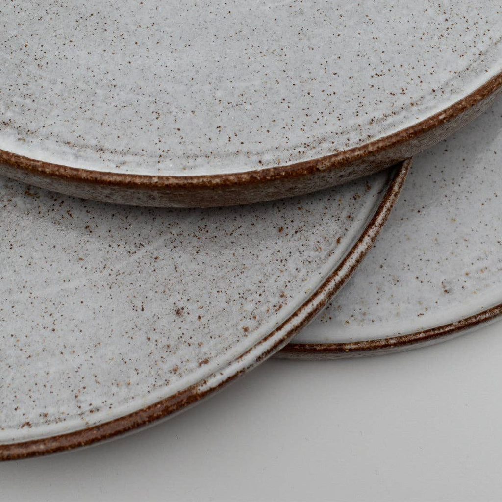 Three ceramic plates with a speckled glaze and brown rim on a white background