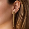 Gold earring worn by a person with long hair