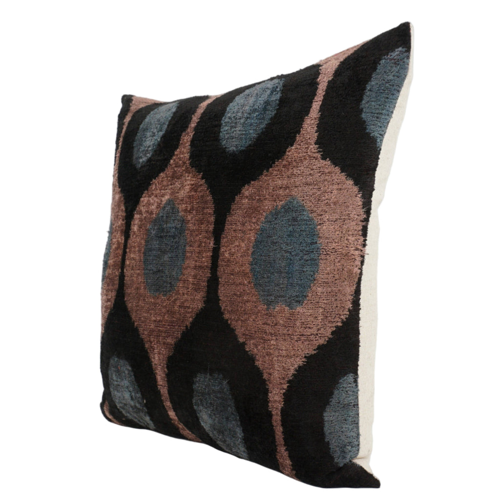 Patterned pillow with brown, black, and teal ovals.