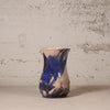 Ceramic vase with abstract design against a textured wall