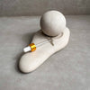 Ceramic dropper bottle with gold cap on a stone surface