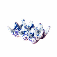 Speckled blue and white ceramic egg holder on a pink background