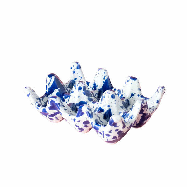 Speckled blue and white ceramic egg holder on a pink background