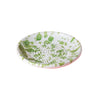 A small round white plate with a green paint splatter pattern, photographed on a solid white background.