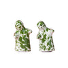 Two small ceramic salt and pepper figurines with a green and white splatter pattern, standing side by side on a solid pink background