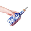 Hand holding a blue and white patterned bottle against a pink background
