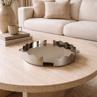 Round wooden coffee table with a decorative metal tray in a living room setting.
