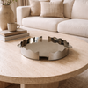 Round wooden coffee table with a decorative metal tray in a living room setting.
