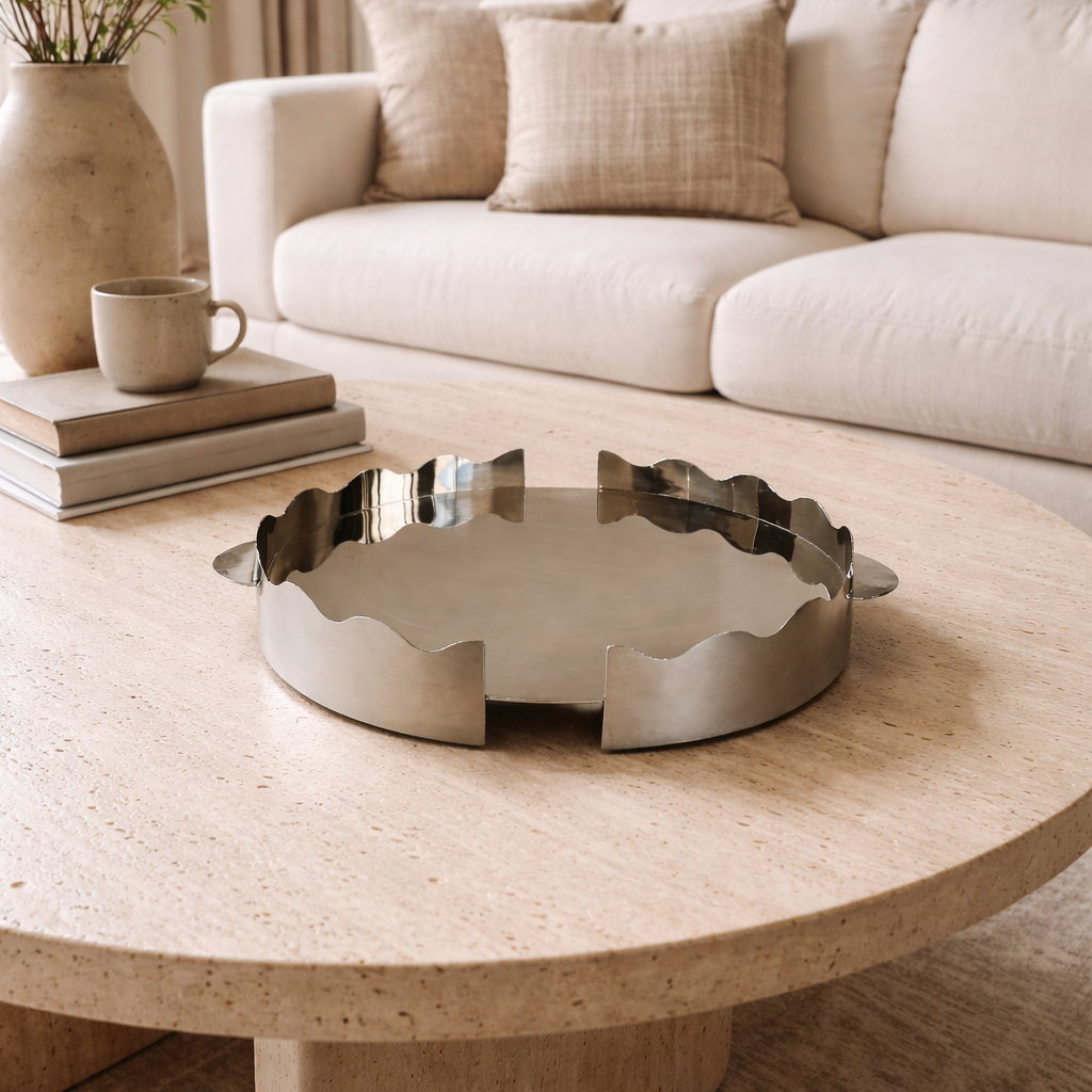 Round wooden coffee table with a decorative metal tray in a living room setting.