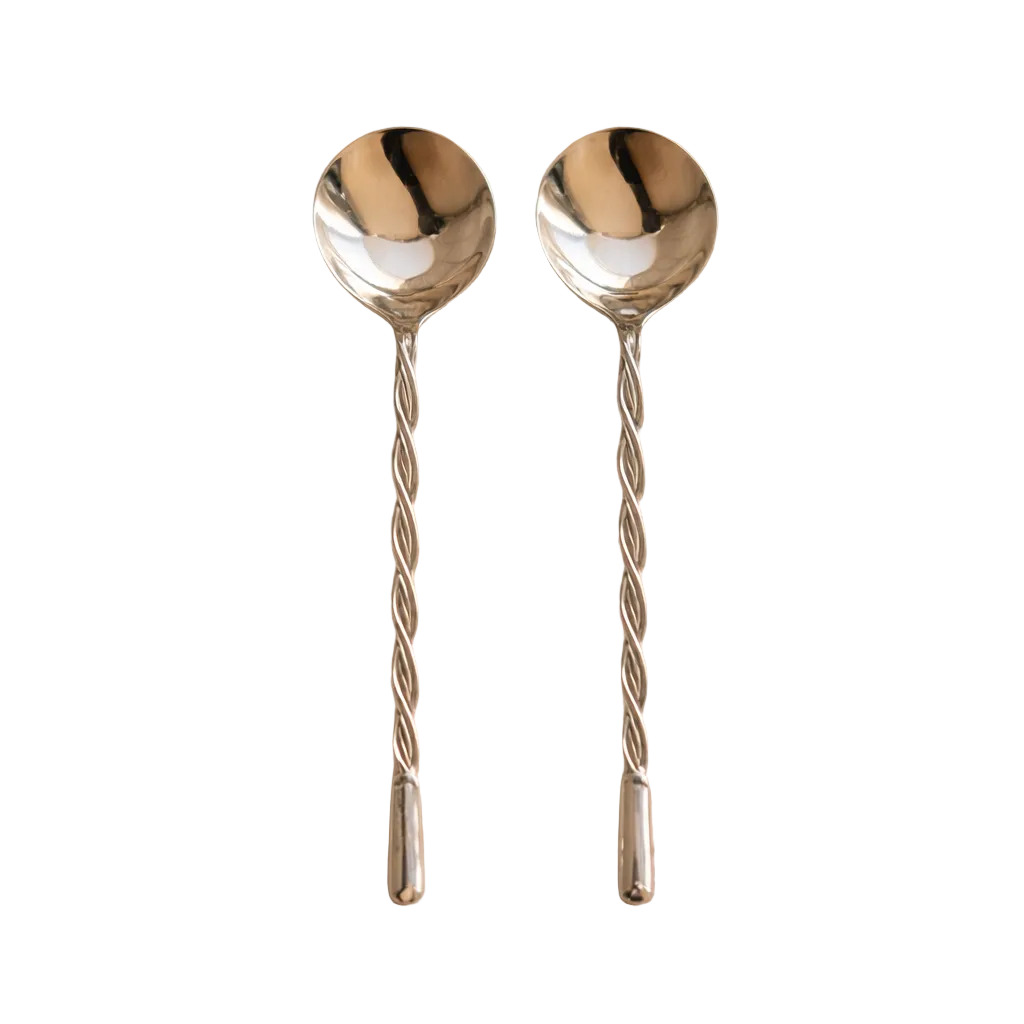 Two silver spoons with twisted handles on a beige background