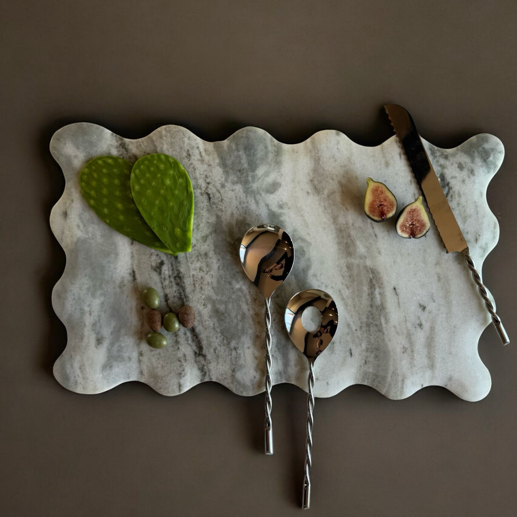 Marble cutting board with figs, a knife, and spoons on a brown background