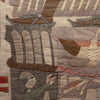 A close-up of a vintage patchwork quilt featuring stitched scenes of sailing ships, a lighthouse, and a sailor in muted tones of beige, brown, gray, and dusty pink.