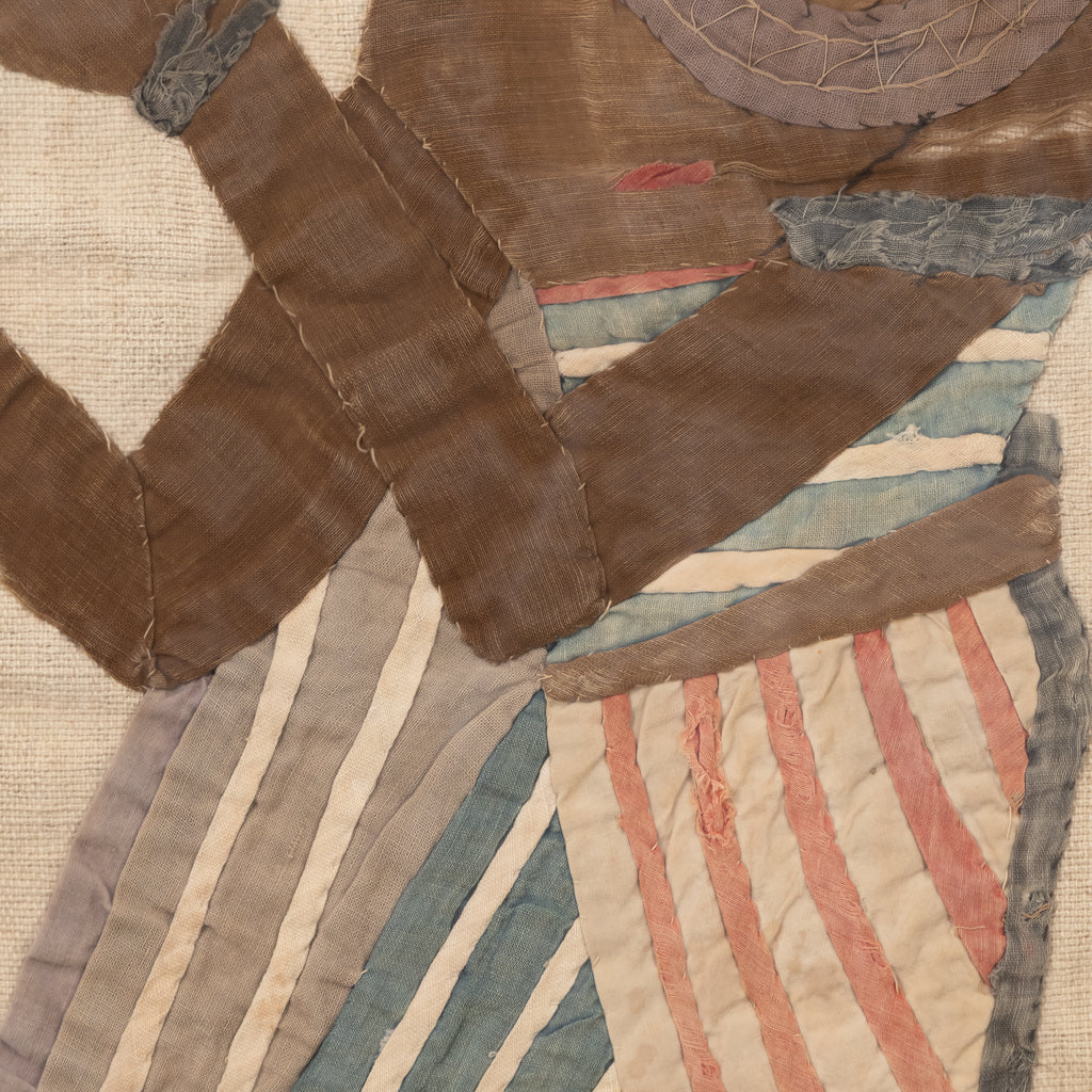A close-up of a handmade patchwork quilt featuring geometric shapes and stripes in earthy tones of brown, beige, muted blue, and dusty pink.