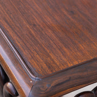 Close-up of a dark brown wooden table corner showing the rich wood grain and polished finish.