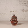 Ceramic jar with a lid on a textured surface with a neutral background