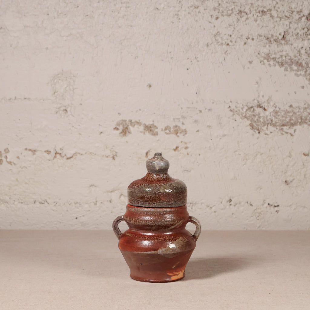 Ceramic jar with a lid on a textured surface with a neutral background