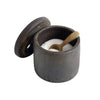 Dark ceramic salt cellar with wooden spoon on a white background