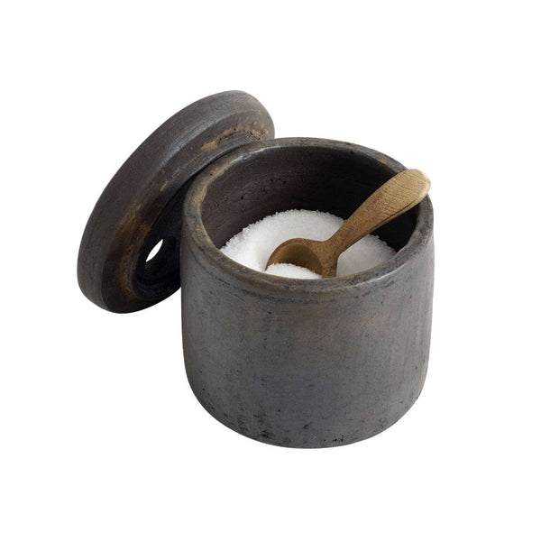 Dark ceramic salt cellar with wooden spoon on a white background
