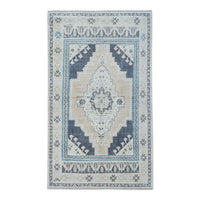 A rectangular area rug with a traditional medallion pattern in beige, light blue, and navy, shown flat against a white background.