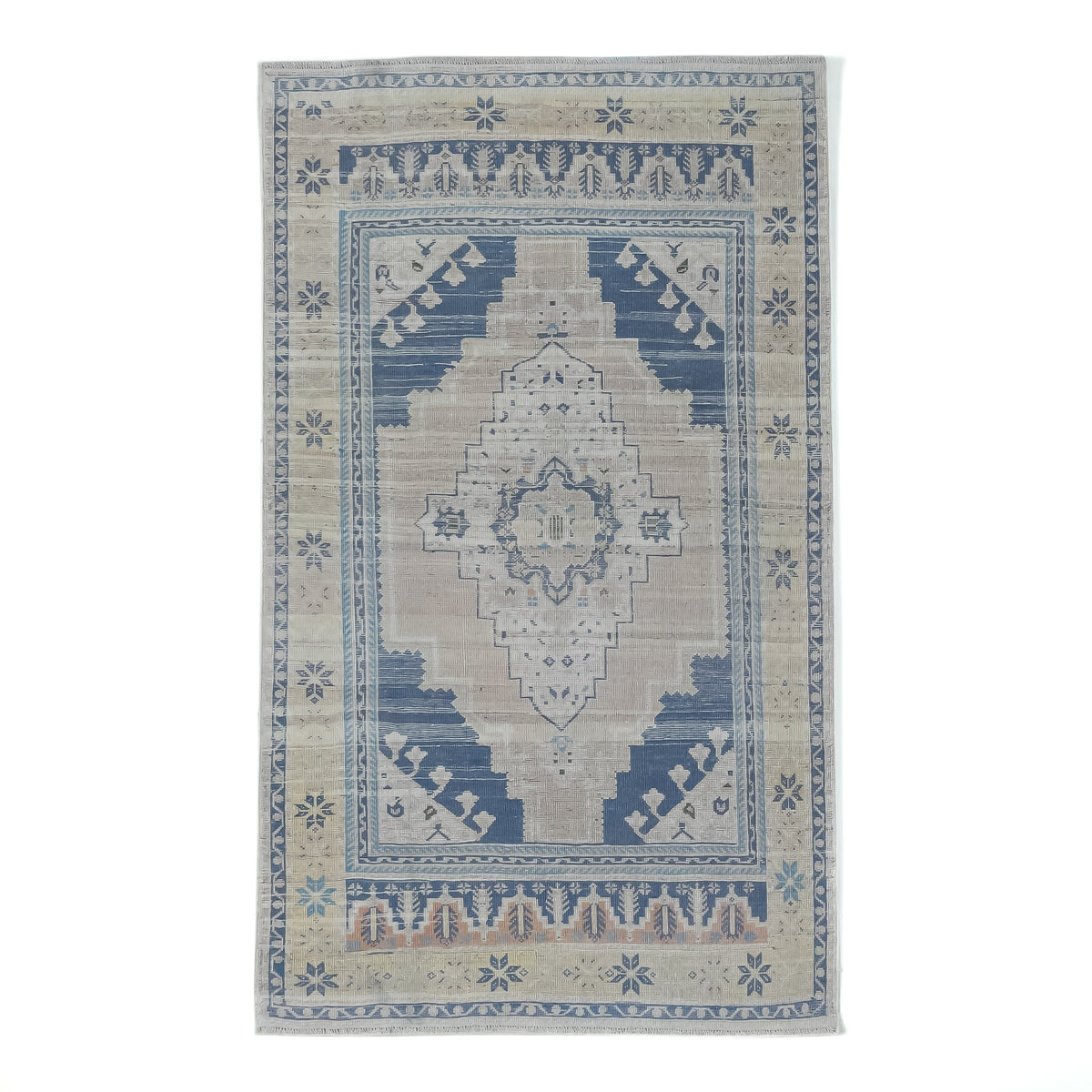 A rectangular area rug with a distressed traditional pattern, featuring a central medallion and geometric borders in shades of blue, beige, and cream on a white background.