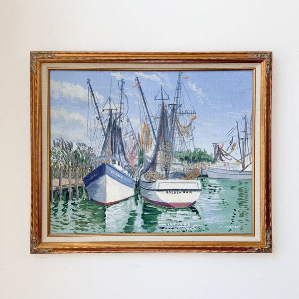 Framed painting of boats docked at a harbor on a white wall