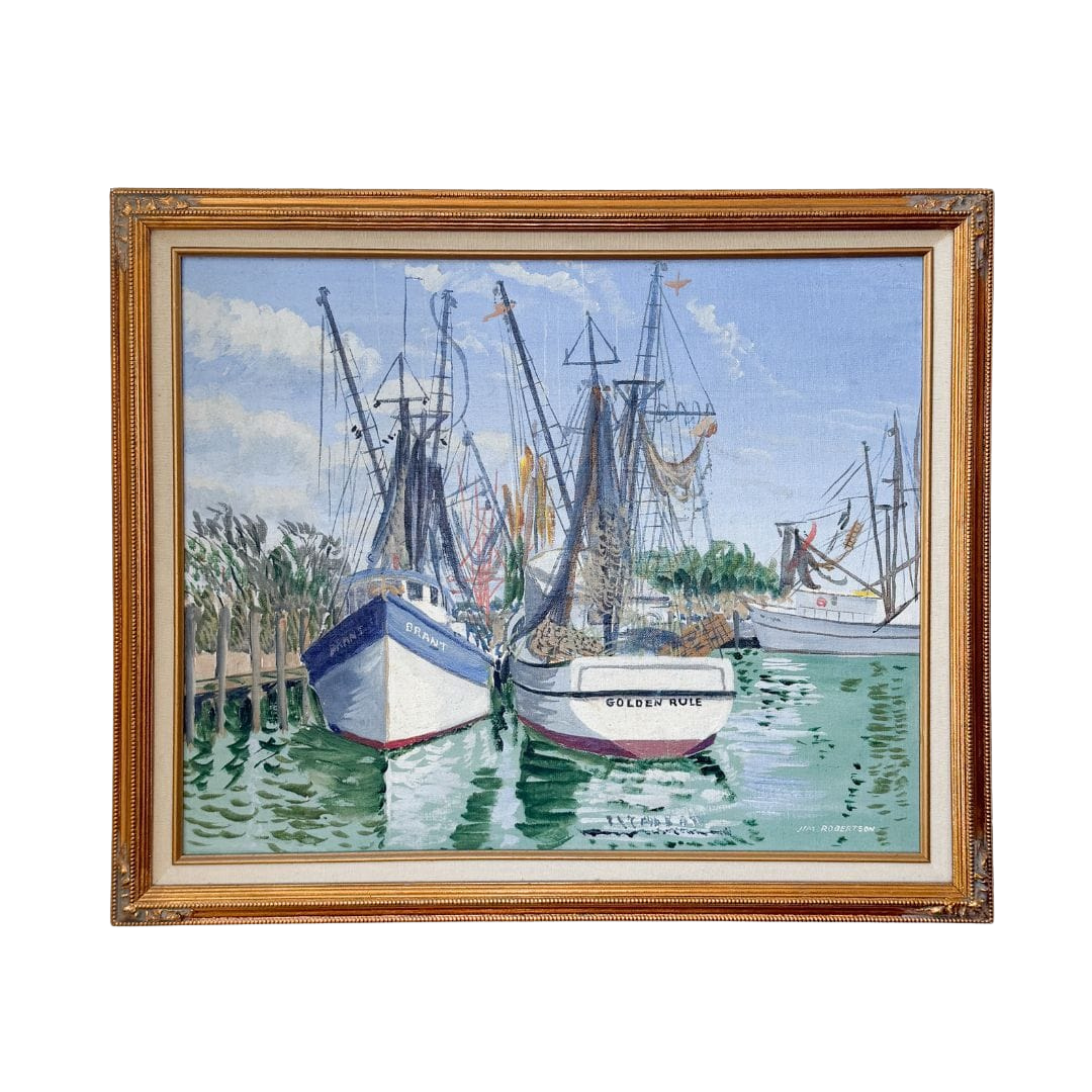 A framed watercolor painting of harbor boats on the water, enclosed in a decorative gold-toned wooden frame. The painting depicts several fishing boats moored in green water under a blue sky with white clouds.