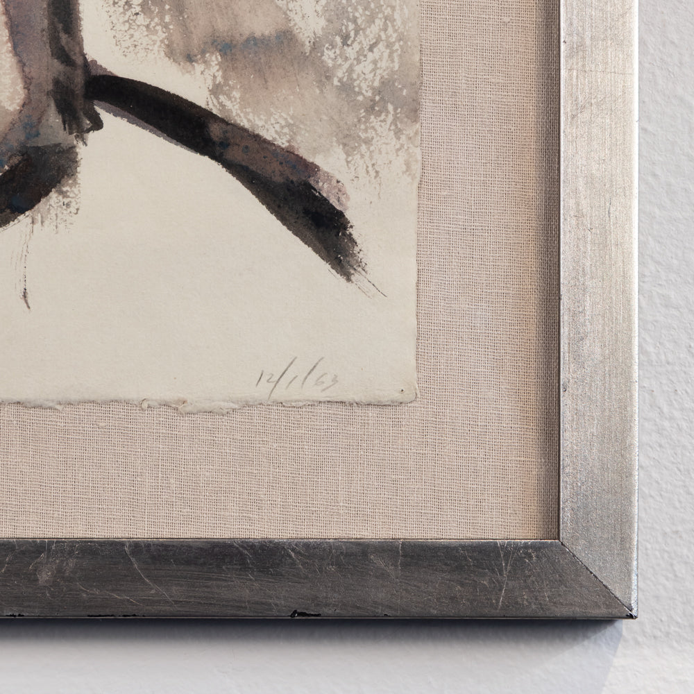 Close-up of framed wall art showing part of an abstract painting with dark brushstrokes on textured off-white paper, set in a light beige mat and a dark gray wood frame against a white wall.