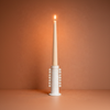 Tall white candle in a decorative holder against a warm brown background
