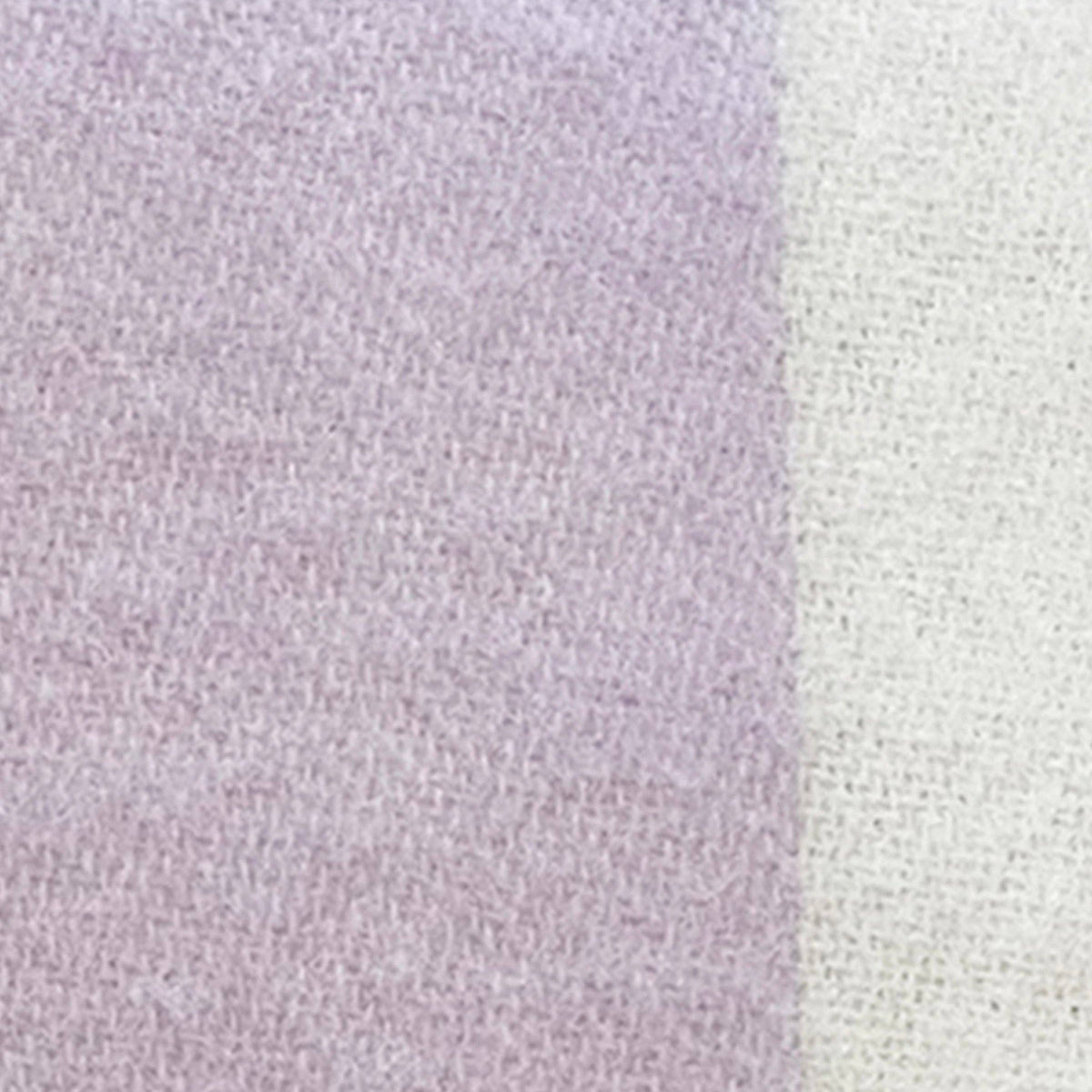 A close-up of a soft knit fabric texture showing a vertical color-blocked pattern with lavender purple on the left and off-white/cream on the right.