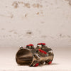 A wide silver cuff bracelet decorated with multiple red cabochon stones and textured silver bezel settings, photographed on a light textured surface with a neutral background.