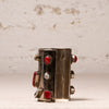 A wide silver cuff bracelet decorated with red gemstones and a central white pearl, displayed on a light textured surface against a neutral background.