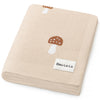 Beige blanket with mushroom design and 'Bleu Lo La' label on a white background
