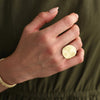 Hand wearing a gold ring on a green background