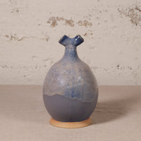 Ceramic vase with blue and beige glaze on a textured surface