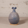 Ceramic vase with blue and beige glaze on a textured surface