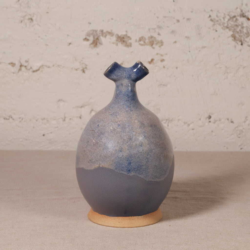 Ceramic vase with blue and beige glaze on a textured surface