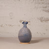 Blue ceramic vase on a beige surface with a textured wall background