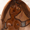 Close-up of a terracotta-colored ceramic sculpture depicting a stylized female face and upper torso with dark brown linework and small light blue accents.